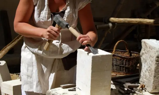 Un artisan tailleur de pierre travaille la pierre avec un marteau et un ciseau.