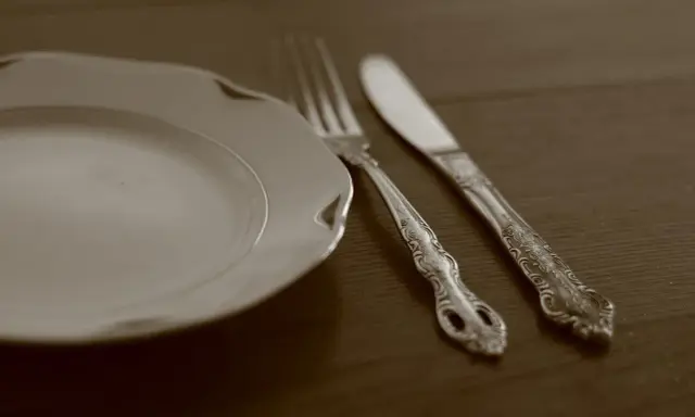 Une assiette blanche et des couverts en métal argenté, prêts pour un repas. L'art de nettoyer des couverts en métal argenté pour qu'ils brillent.