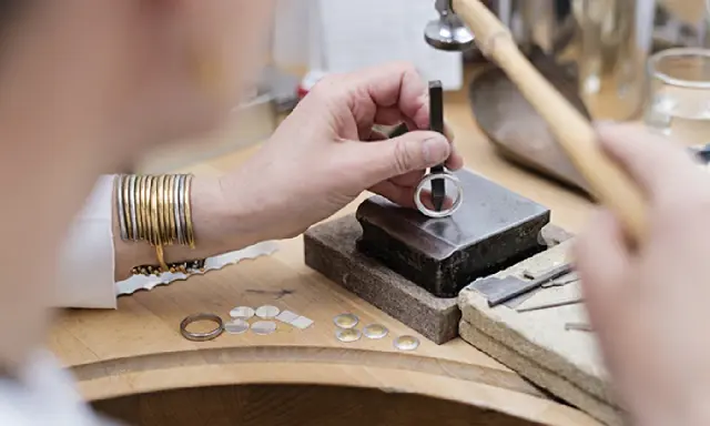 Un orfèvre au travail, façonnant une bague avec précision. Son métier d'orfèvre demande patience et dextérité.