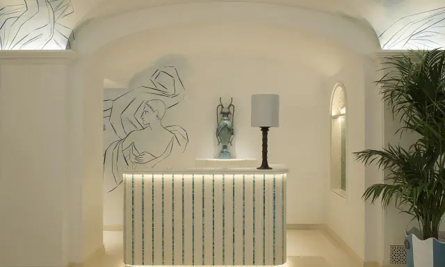 L'entrée art déco dévoile une réception lumineuse, ornée de fresques murales et d'une plante luxuriante.