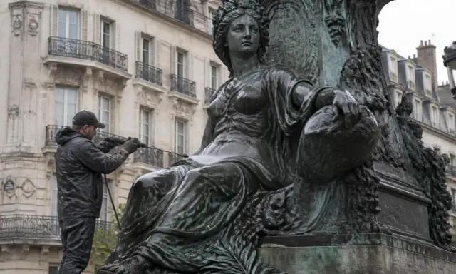 Un homme nettoie une statue en bronze avec un jet d'eau. Il apprend comment nettoyer le bronze pour redonner son éclat à l'œuvre.