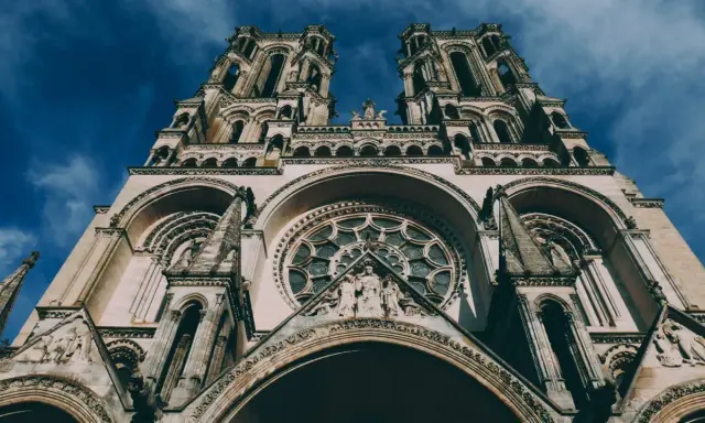 La **cathédrale de Laon**, majestueuse et imposante, se dresse sous un ciel bleu profond. Ses tours jumelles et sa rosace ornée captivent le regard.