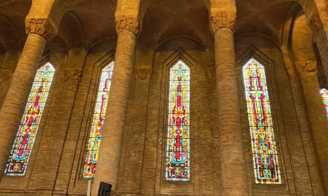 Vitraux colorés illuminant l'intérieur de l'église de Gien, encadrés par de hautes colonnes de briques.