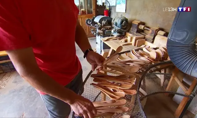 Un artisan du bois, maître dans son métier de tabletier, présente une collection de cuillères en bois faites à la main.
