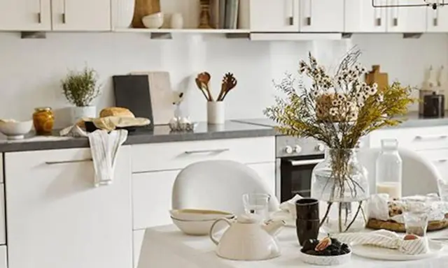 Cuisine lumineuse et aérée, style cottage. Table dressée avec théière, fleurs séchées et pain frais.