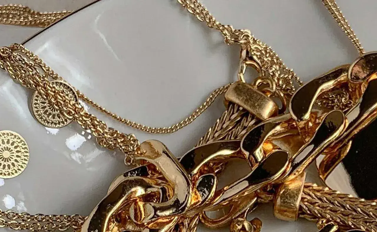 Un bain d'or pour bijoux : des chaînes épaisses et fines, des pendentifs ronds ajourés, un amas de luxe scintillant.