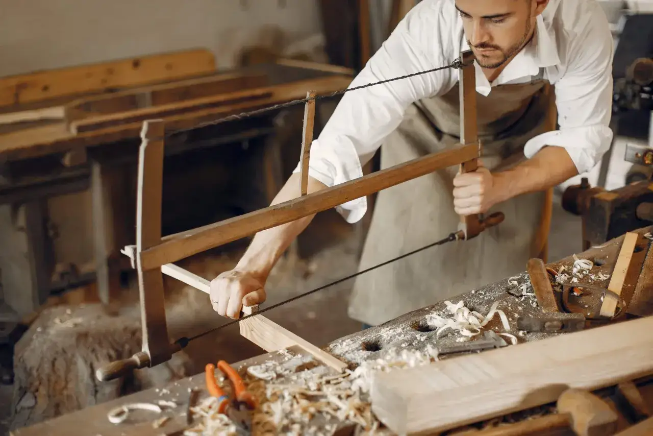 Un homme apprend comment devenir artisan d'art en travaillant le bois dans son atelier.