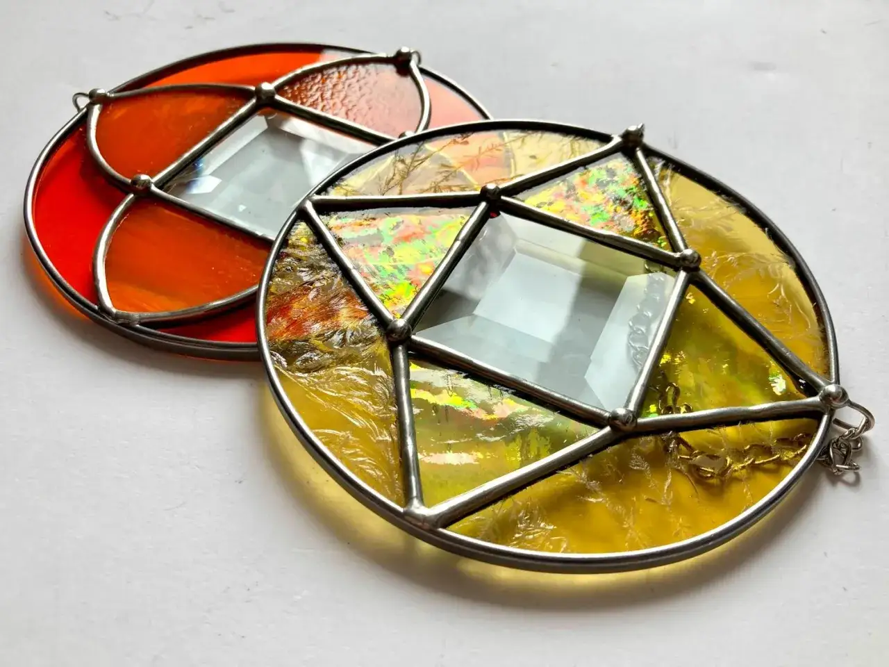 Deux ornements circulaires en vitrail, un rouge orangé, l'autre jaune irisé. Un dessin vitrail facile pour décorer.