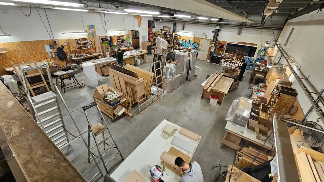 Atelier de travail animé, où l'on peut apercevoir des planches de bois, des outils et des projets en cours, témoignant d'une passion pour l'ébénisterie d'art.