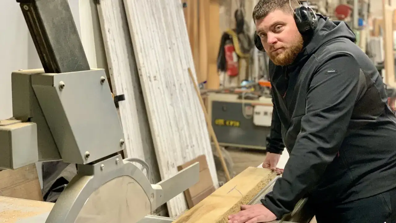 Un artisan qui travaille le bois, concentré, utilise une scie circulaire dans son atelier.