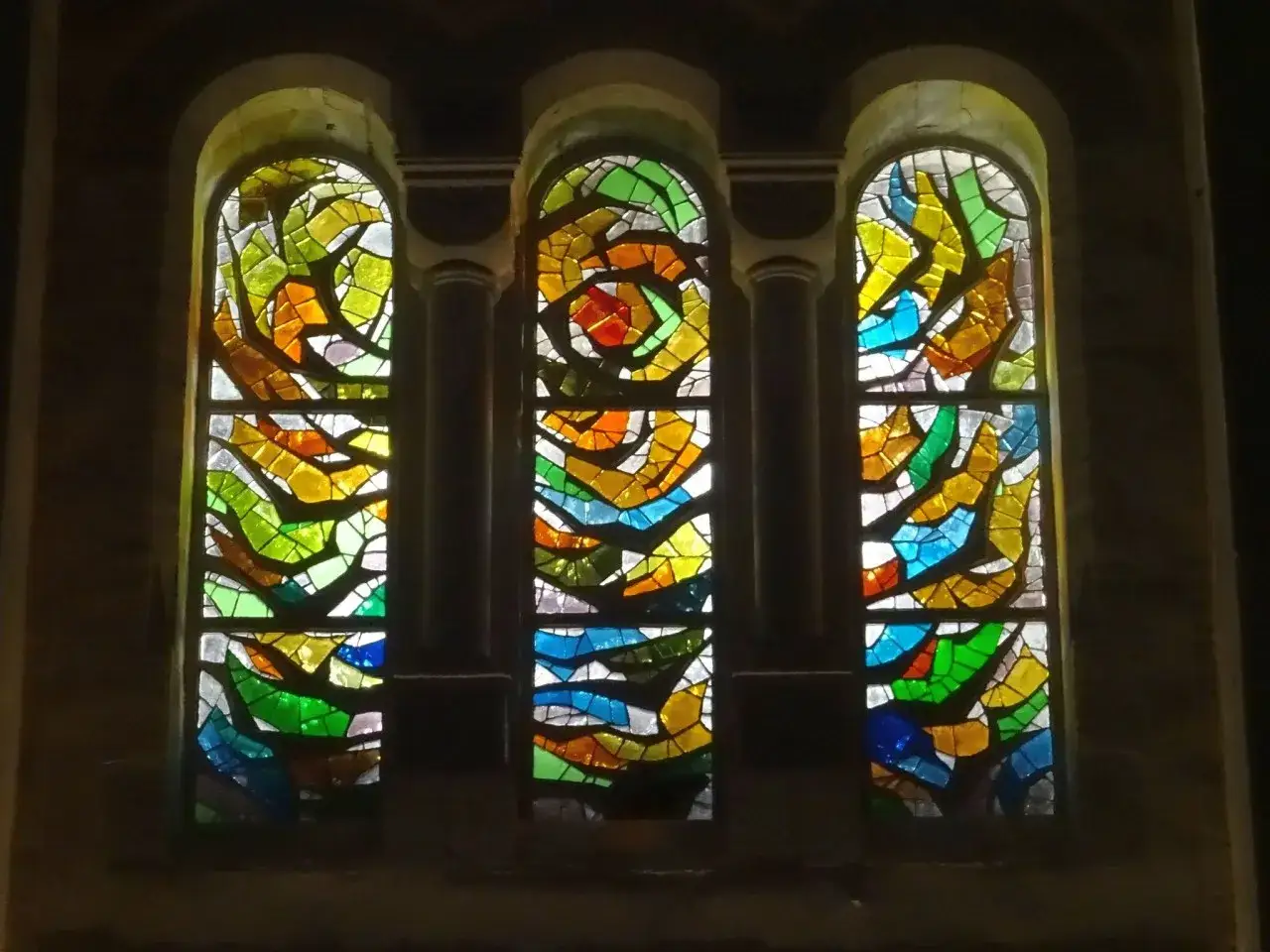 Trois vitraux aux formes abstraites et aux couleurs vives, un exemple de comment &eacute;clairer un vitrail pour r&eacute;v&eacute;ler sa beaut&eacute;.