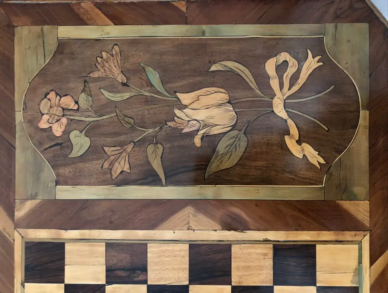 Incrustation florale sur bois, &oelig;uvre d'un artisan &eacute;b&eacute;niste. Un ruban et des fleurs d&eacute;licates en marqueterie.