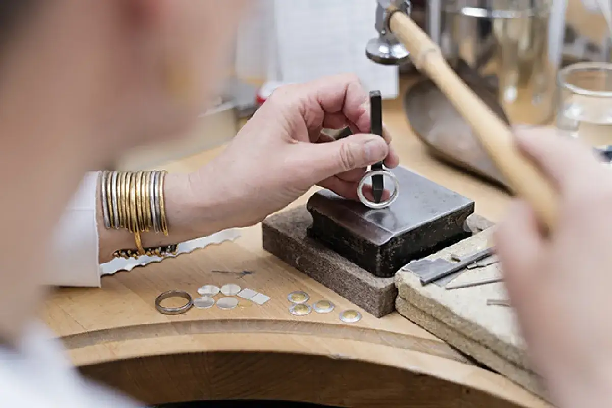 Un orf&egrave;vre au travail, fa&ccedil;onnant une bague avec pr&eacute;cision. Son m&eacute;tier d'orf&egrave;vre demande patience et dext&eacute;rit&eacute;.