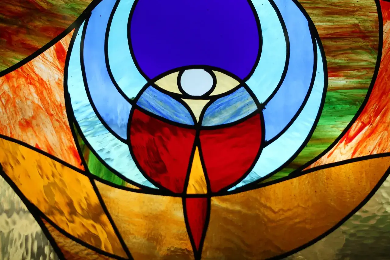 Un vitrail abstrait aux couleurs vives, évoquant un soleil rayonnant. Le verre soleil capture la lumière, créant un spectacle visuel.