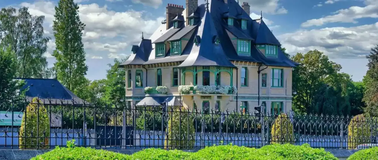 Magnifique maison demoiselle à Reims, avec ses toits bleus et ses ornements verts. Un portail en fer forgé protège ce joyau architectural.