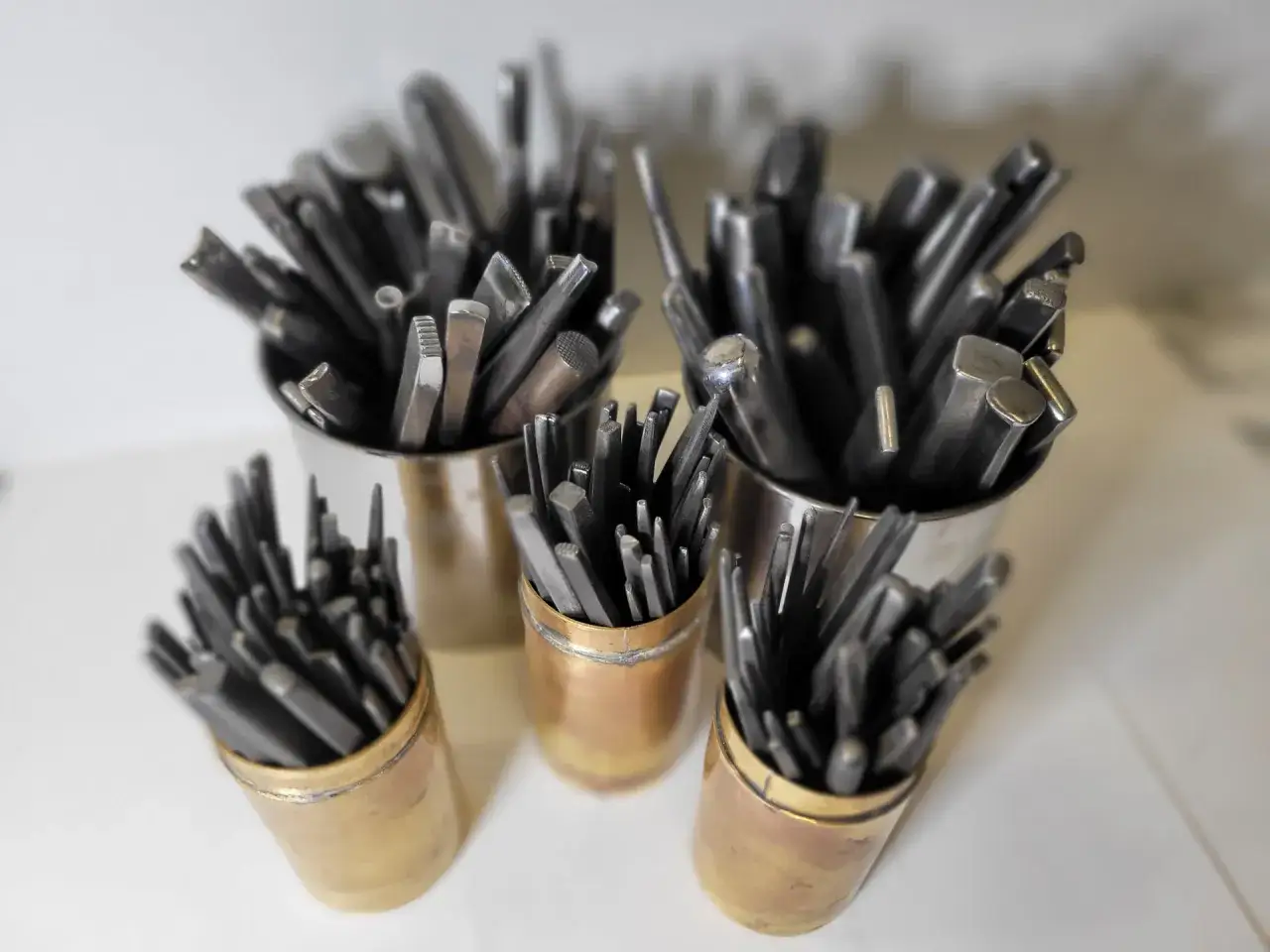 Ensemble d'outils de orf&egrave;vre dans des pots en m&eacute;tal et en laiton, pr&ecirc;ts &agrave; fa&ccedil;onner le m&eacute;tal pr&eacute;cieux.