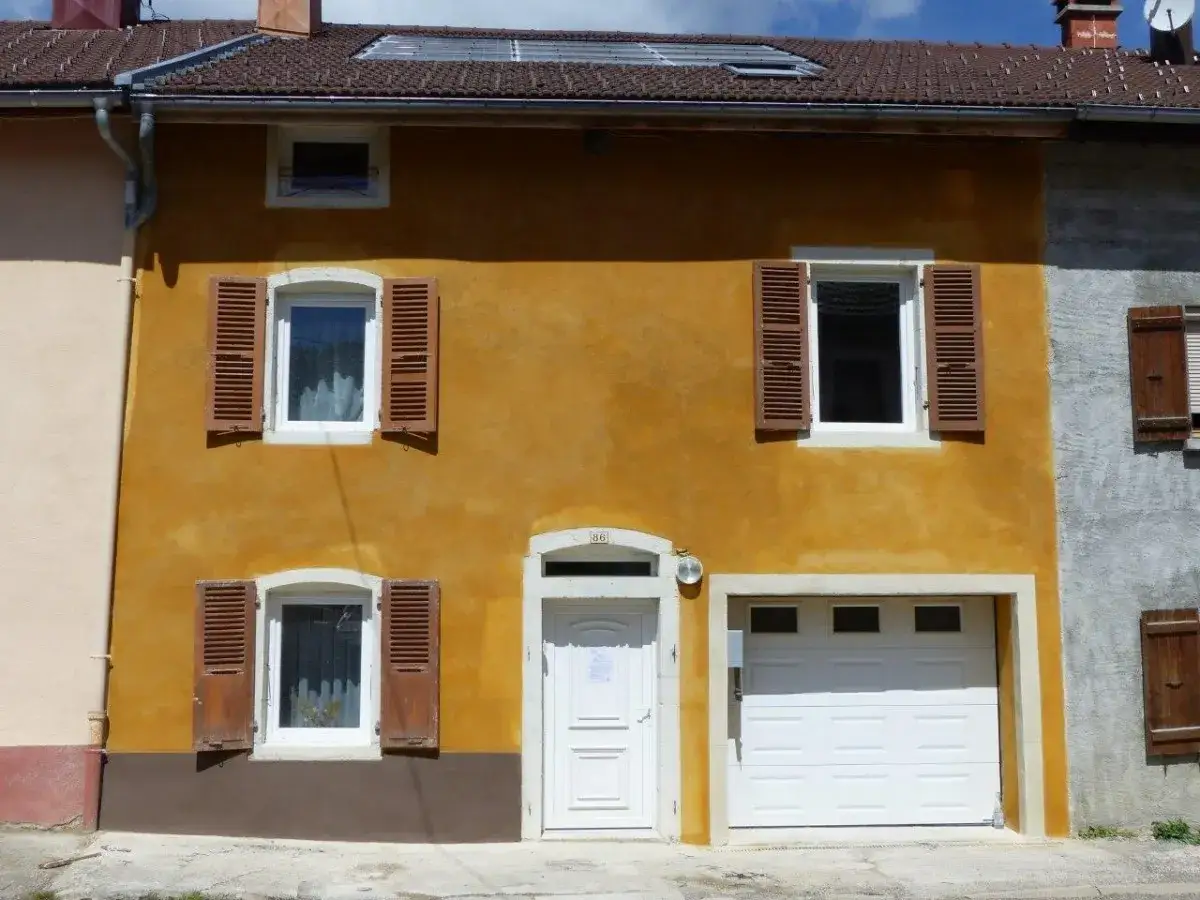Fa&ccedil;ade ocre d'une maison avec volets en bois marron. La chaux morte a &eacute;t&eacute; appliqu&eacute;e sur le mur, lui donnant une texture unique.