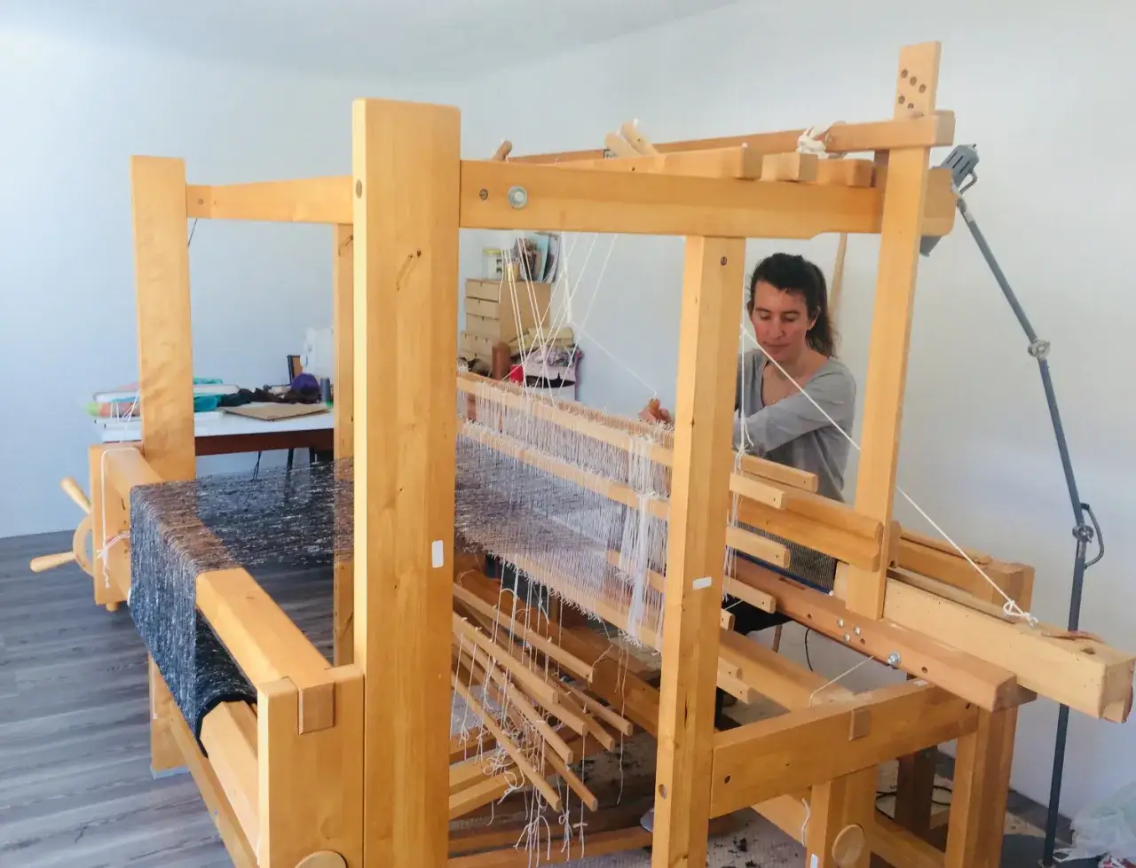 Une femme pratique le tissage sur un métier en bois. Un art ancestral, le tissier métier, prend vie sous ses mains habiles.