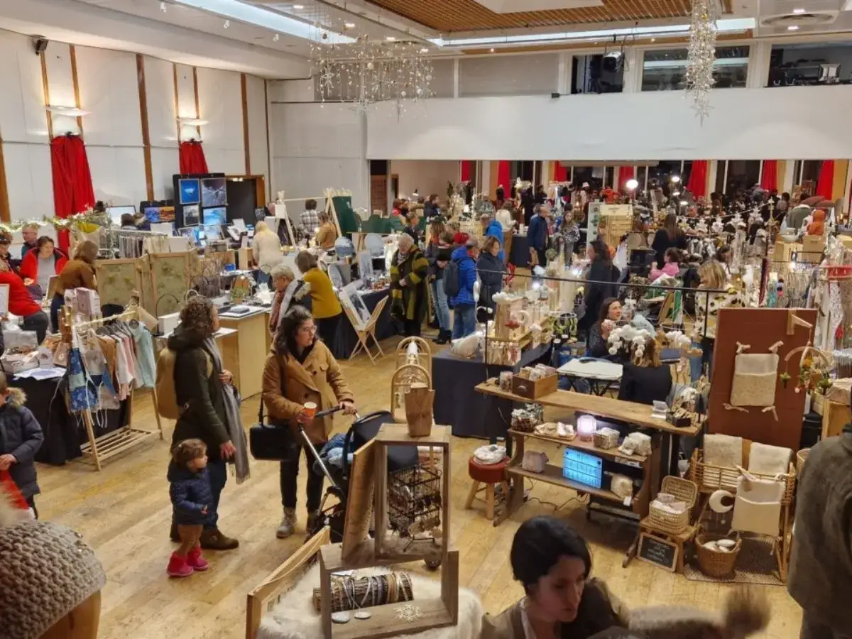 Foule dans un march&eacute; de No&euml;l, d&eacute;couvrant l'artisanat &agrave; Annecy. Stands remplis de cr&eacute;ations uniques, ambiance chaleureuse.