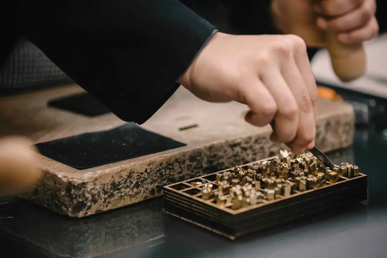 Main d'artisan sélectionnant des poinçons en laiton pour un travail d'artisanat de luxe.