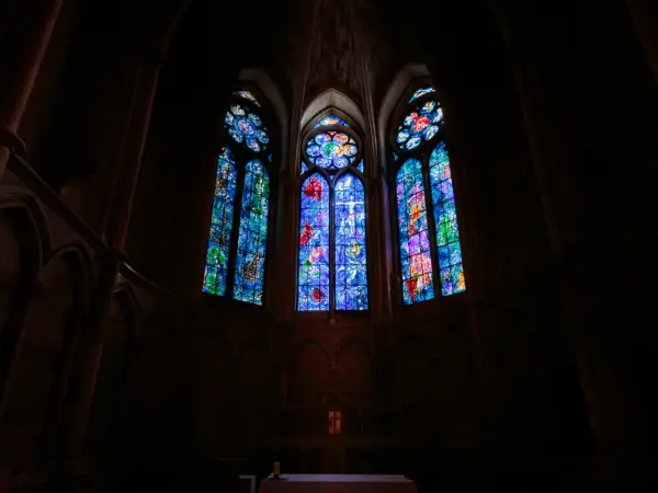 Vitraux de Chagall à Reims, illuminant l'intérieur sombre d'une cathédrale gothique.