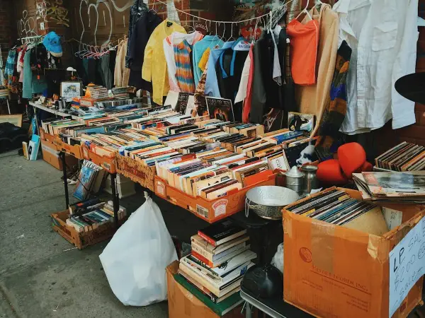 Un étalage de brocante rempli de livres, disques vinyles et vêtements. Les livres sont les objets les plus recherchés en brocante, et cette sélection en est la preuve.