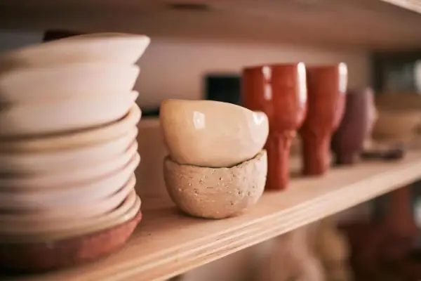 Sur une étagère en bois, des bols et des gobelets en terre cuite, œuvres d'un céramiste France, attendent d'être vendus.