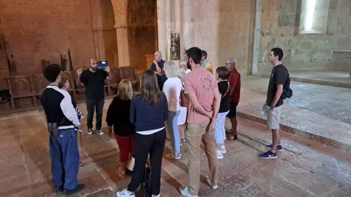 Visite guidée dans l'abbaye du Thoronet. Un groupe de touristes écoute attentivement un guide présentant l'architecture cistercienne.
