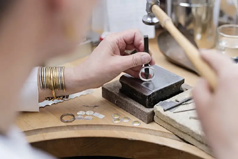 Un orfèvre au travail, façonnant une bague avec précision. Son métier d'orfèvre demande patience et dextérité.